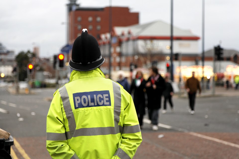 British Policeman Wearing Tradtional Helmet Observes People-See below for more