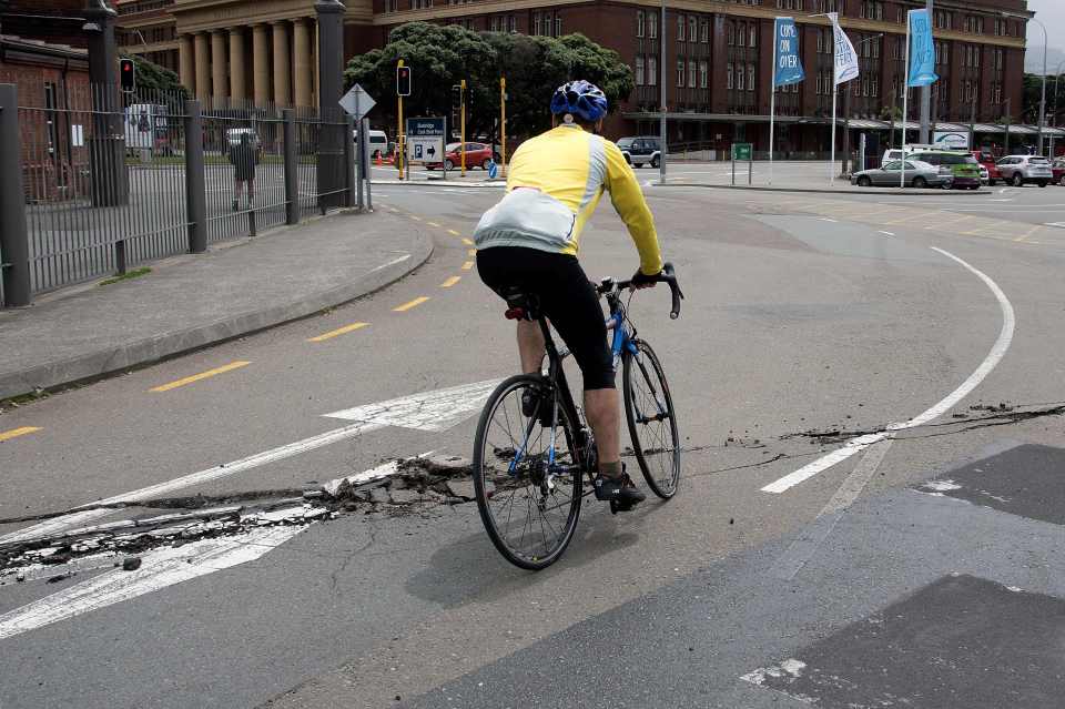  A cyclist rides over a damage road on the Wellington water front