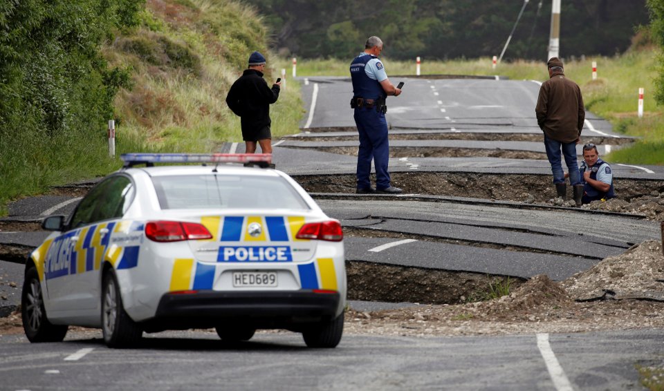  Policemen and locals look at damage following an earthquake, along State Highway One near the town of Ward