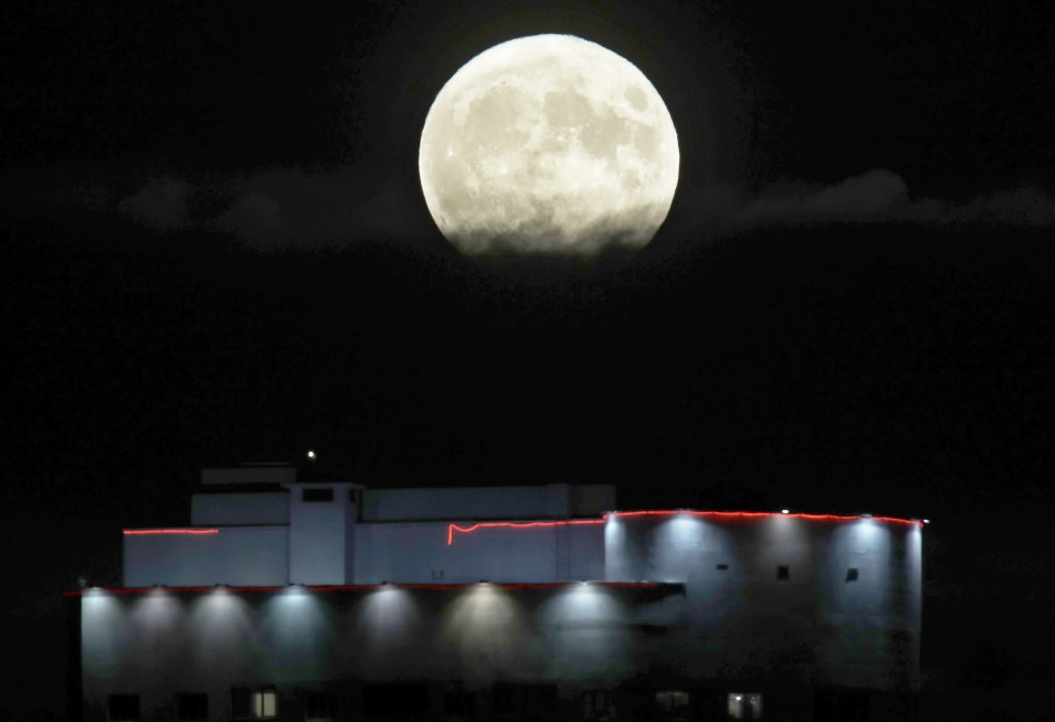  The moon rises from behind the top of an apartment building in Minsk , Belarus