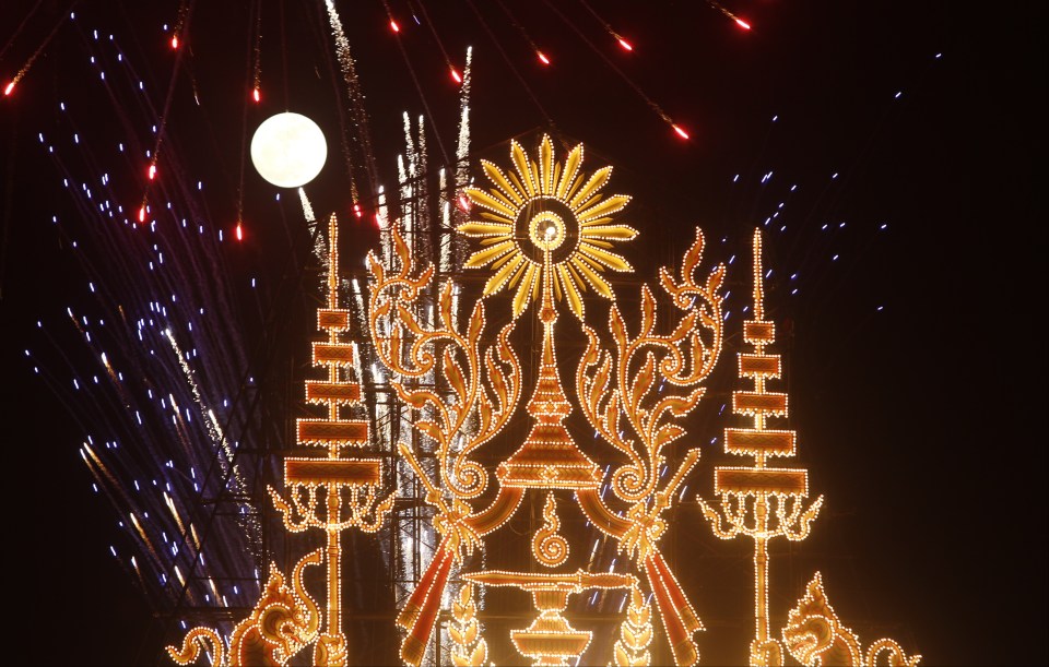  The moon rises over an illuminated wooden boat making the way along the Tonle Sap river for a boat race in front of the Royal Palace in Phnom Penh, Cambodia