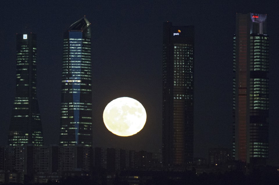  The moon rises behind the four business towers that mark the city skyline in Madrid, Spain