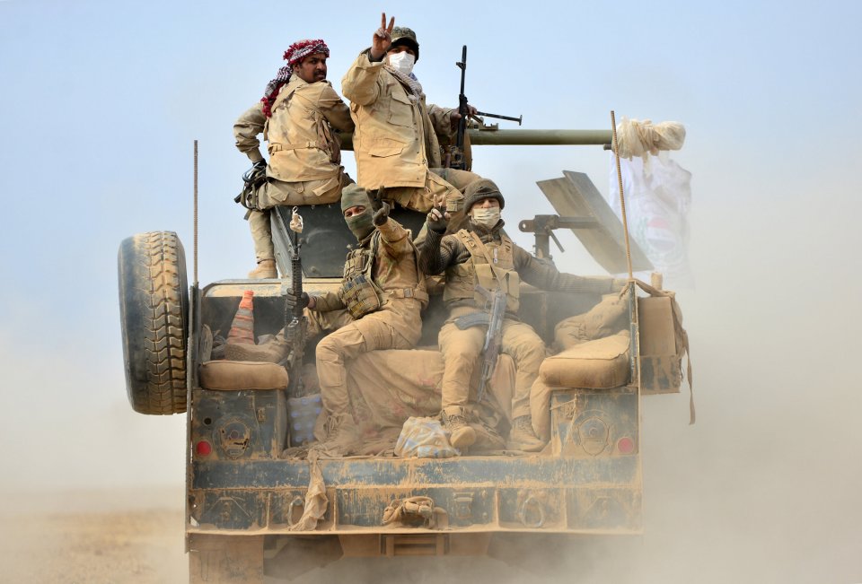 Shi'ite fighters ride on a military vehicle heading toward the airport of Tal Afar during a battle with Islamic State militants in Tal Afar