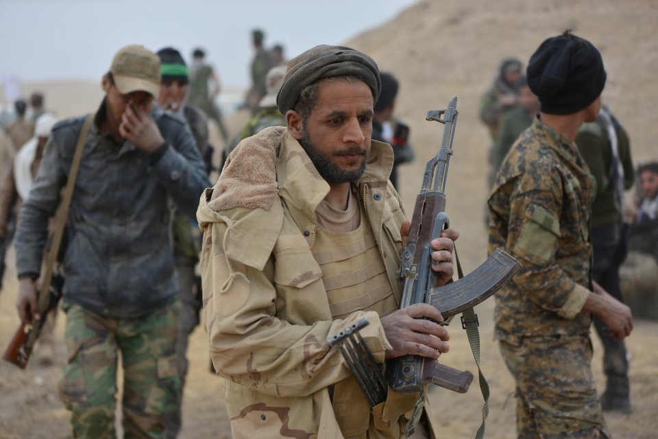 Shi'ite fighters carry weapons during a battle with Islamic State militants in Tal Afar