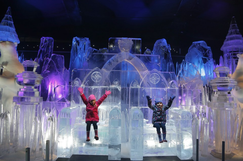  Two young visitors enjoy having their photos taken on thrones made of ice