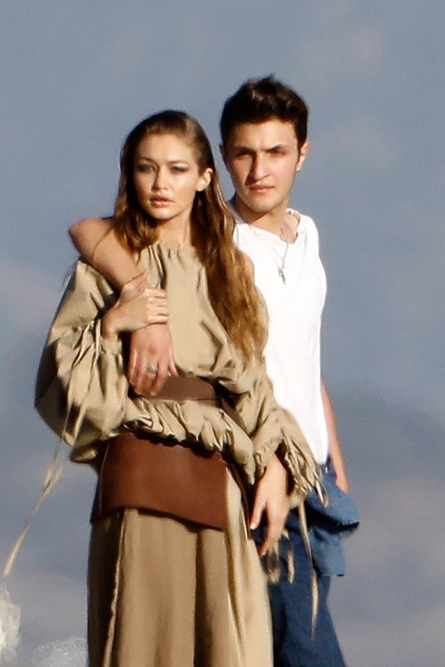 The male model draped his arm around Gigi's neck as they walked along the sand