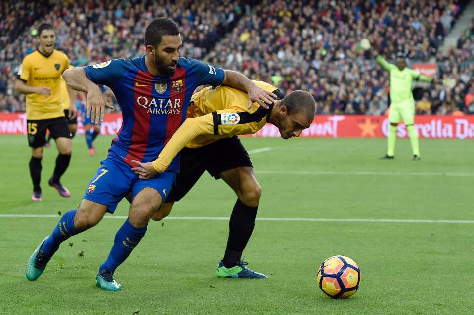  Turkish international Arda Turan takes on Malaga defender Mikel Villanueva