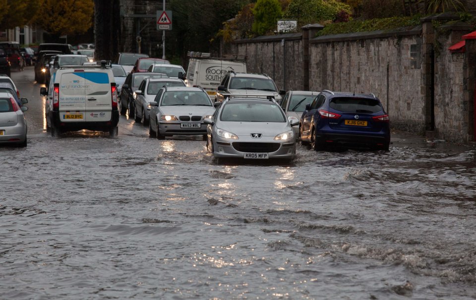  Cars and buses drive along flooded roads in Plymouth, Devon