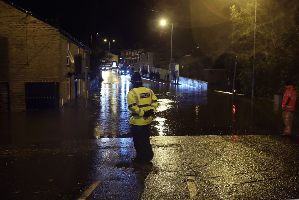  A police officer looks at flooding on Huddersfield Road in Stalybridge, Greater Manchester, as as heavy rain has fallen in the region