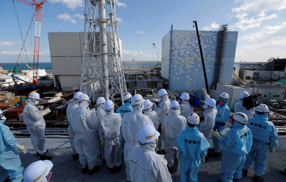  Members of the media, wearing protective suits and masks, receive briefing from Tokyo Electric Power Co.