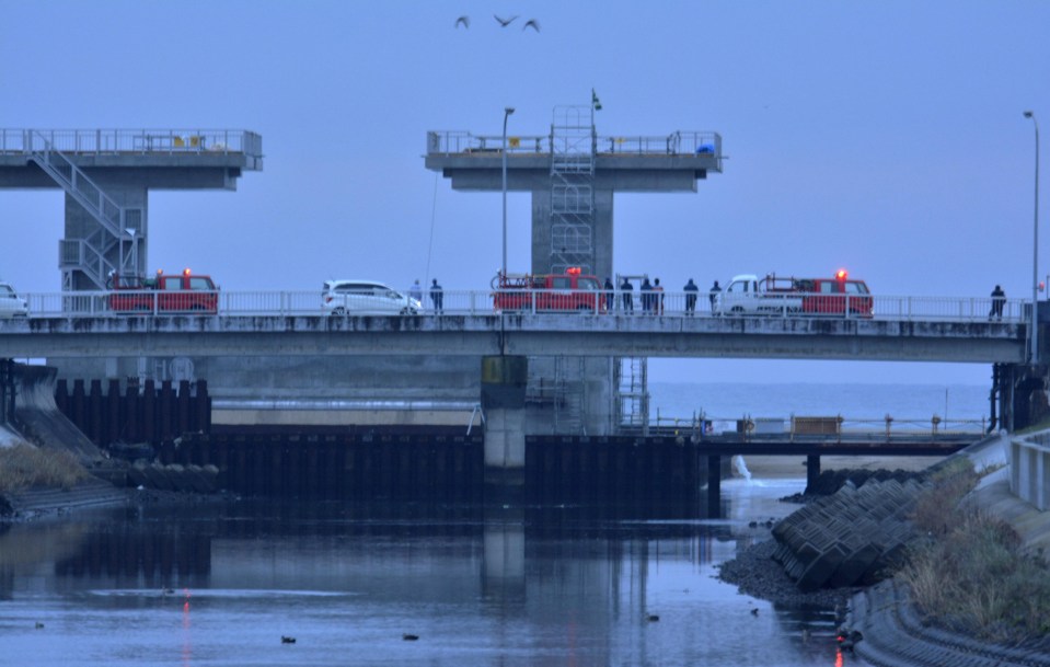  Firefighters and city officials check the water level at an estuary following a tsunami warning in Iwaki,