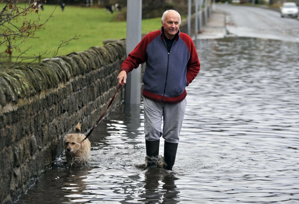  A man and his dog make their way through flood on the A65 near Ilkley, West Yorks