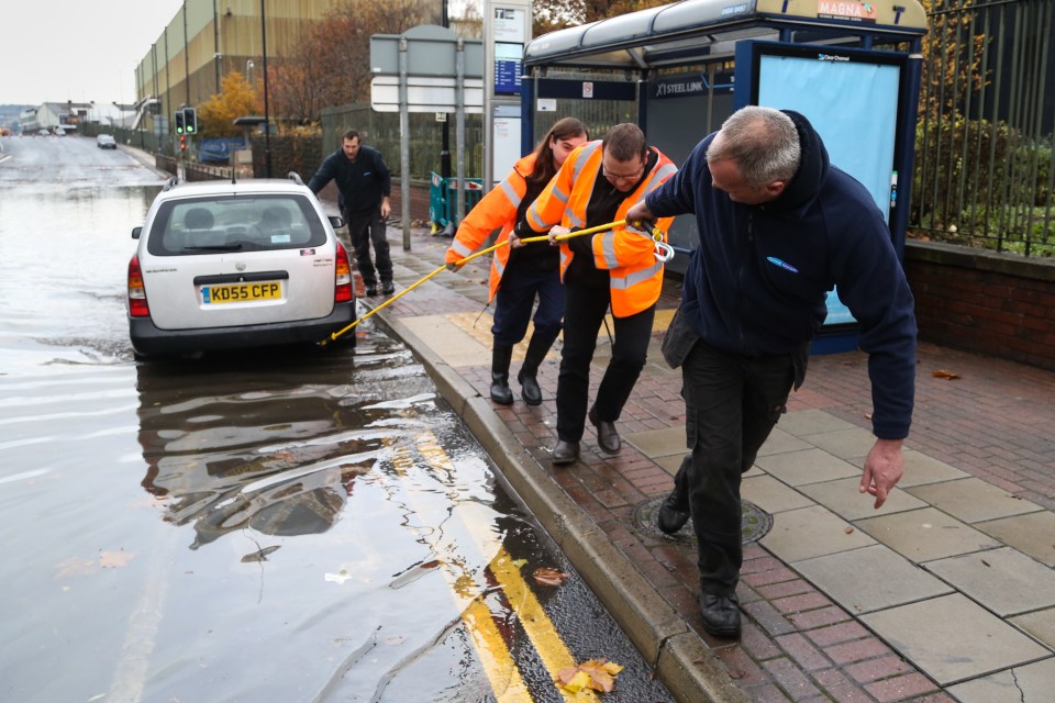  A group of men pull a stranded van free from a flooded road in Rotherham