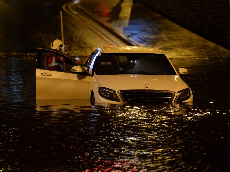  Firefighters rescue a stranded a motorist in floods in Aston-under-Lyne