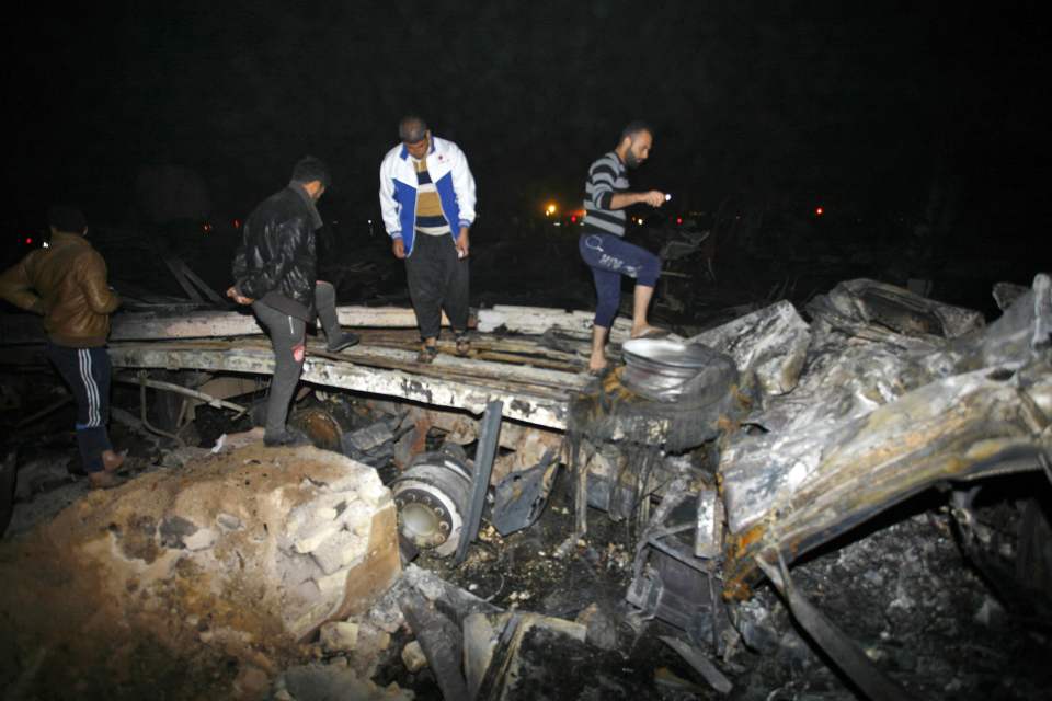  Carnage... People inspect the wreckage of a vehicle following a suicide bombing that targeted Shiite pilgrims in Karbala