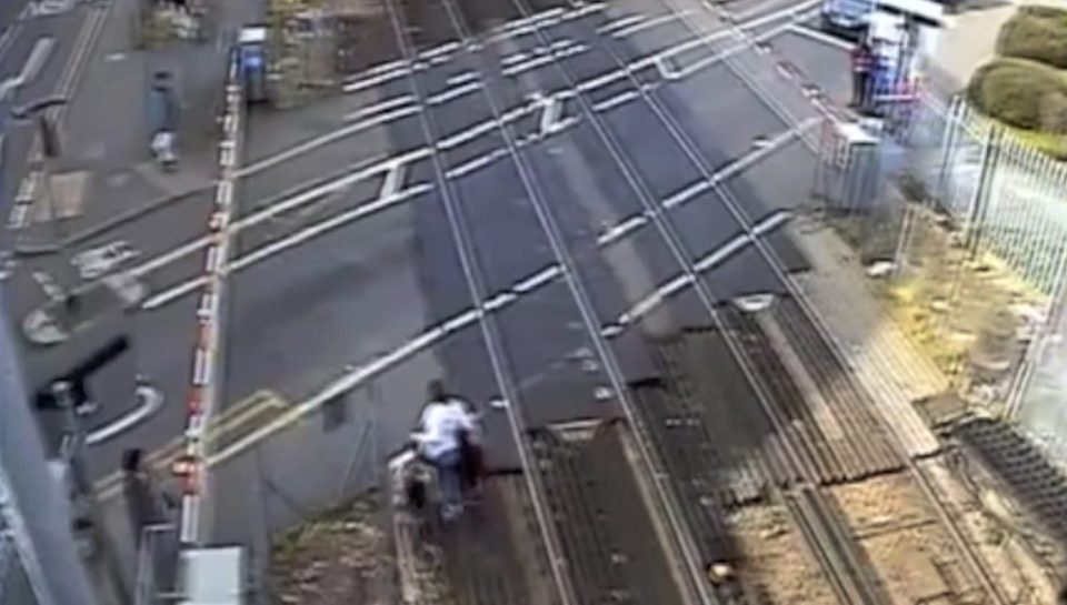  The women can be seen coming up a set of stairs from another platform towards the level crossing, seen on the left