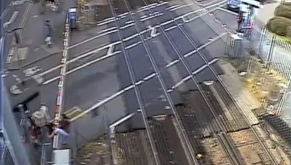  One of the women can then be seen clambering over the barrier at Feltham, West London, herself