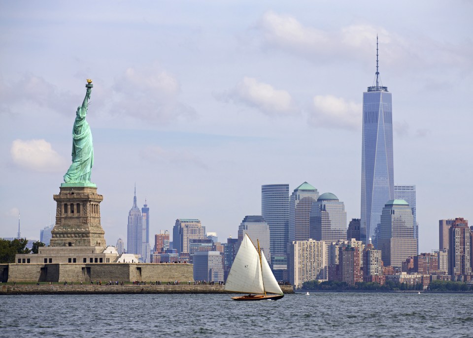 Wooden sailboat cruises along the skyline of New York City