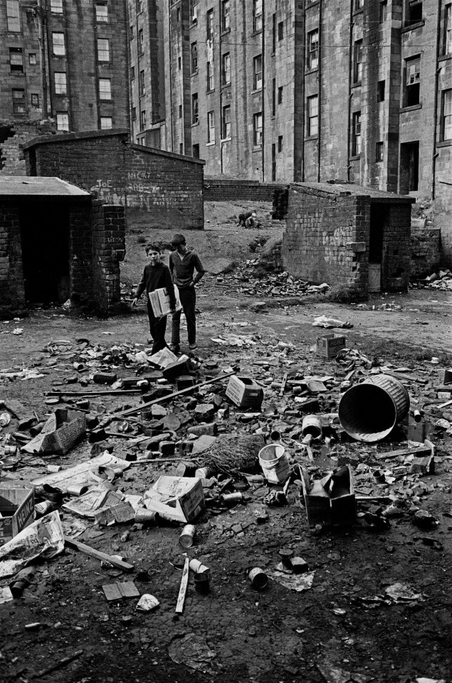  Boys wandering through rubbish, delivering newspapers, Maryhill tenement back 1971