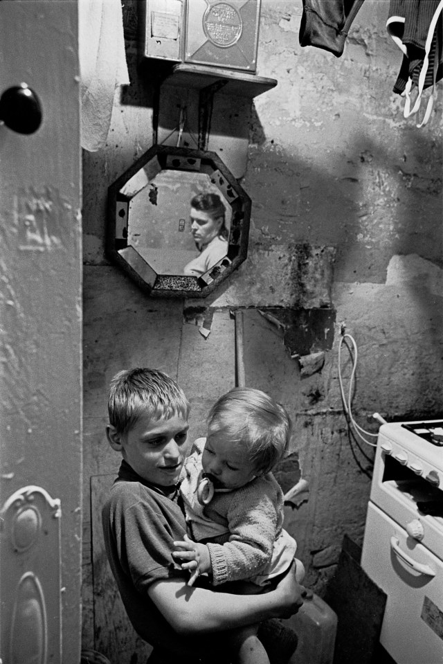  Michael Rump holding the baby, Peggy reflected in mirror, 1969 as his mother watches on