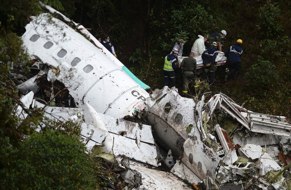  Workers carry a body away from the plane wreckage