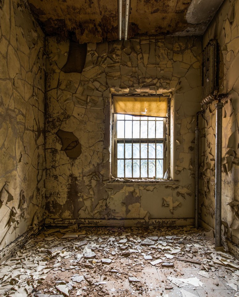  One of the bedrooms, described by the photographer as 'claustrophobic', has crumbling walls and is littered with rubble