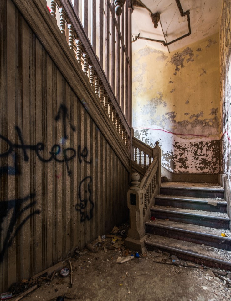  An eerie staircase in the abandoned building is covered in graffiti