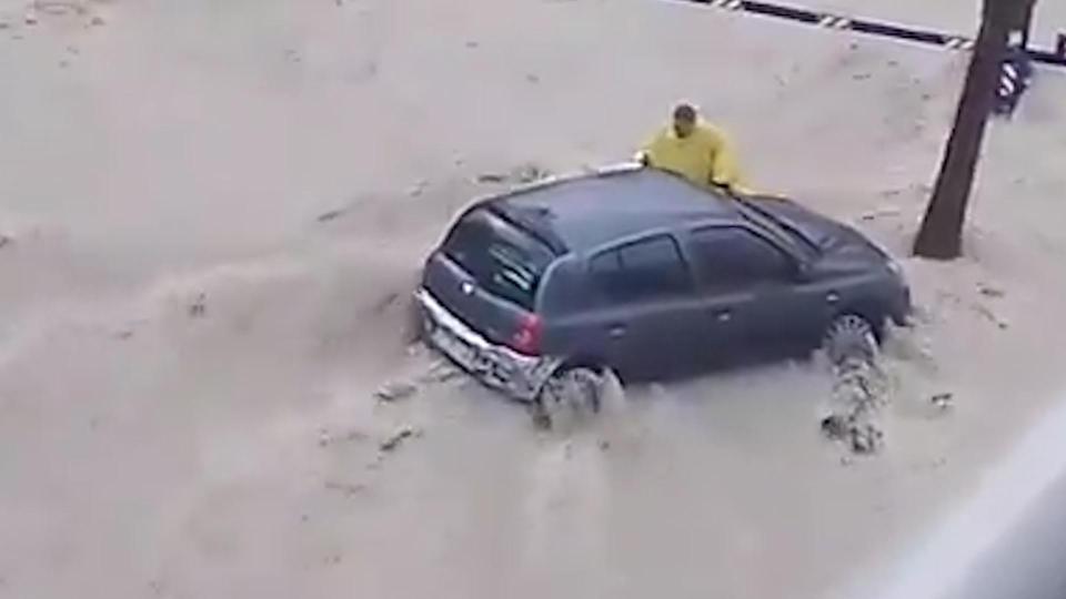  The man is seen trying to reach his car as he attempts to wade through the flood waters