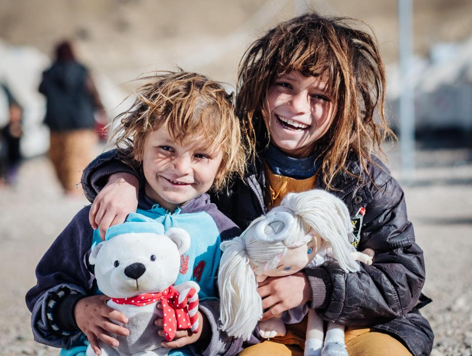  Two Iraqi youngsters hug and hold the donated gifts from The Sun's Smile at Christmas campaign