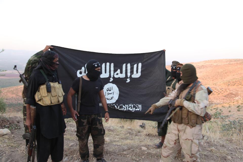 ISIS fighters holding the Al-Qaeda flag with 'Islamic State of Iraq and the Levant' written on it