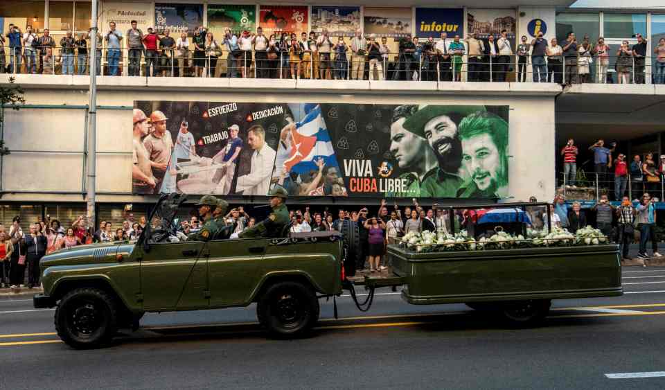  The ashes pass a poster showing other revolutionary leaders including Che Guevara