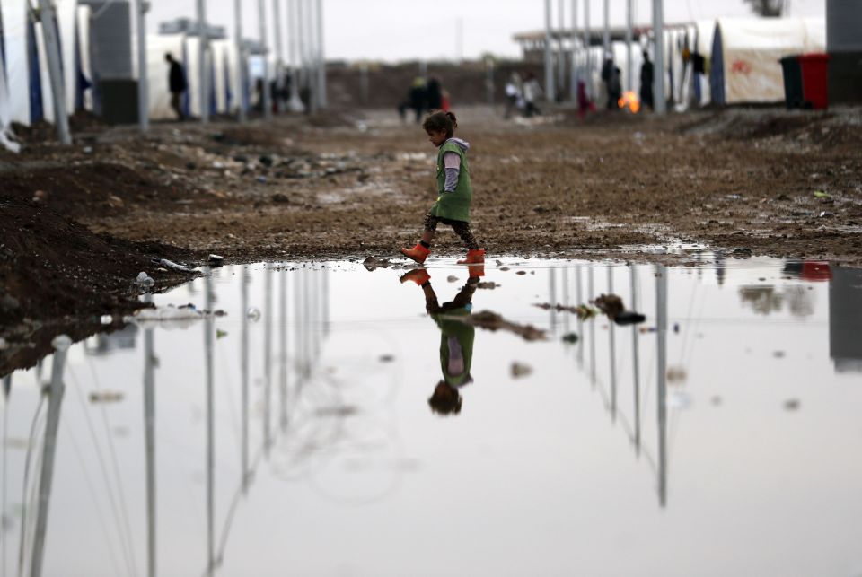  Refugees were pictures trudging along in the mud in migrant camps