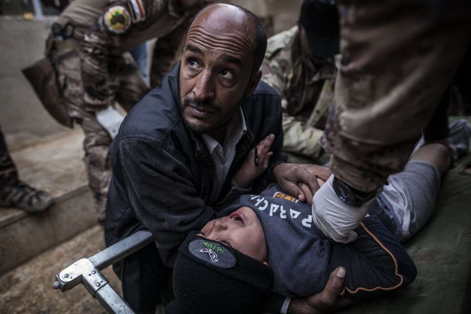  An Iraqi man holds his son who was wounded by an explosion in Mosul