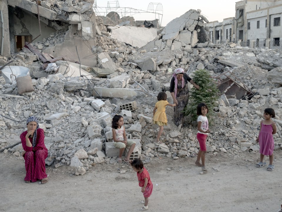  A family stands on what is left of their home in Syria last year