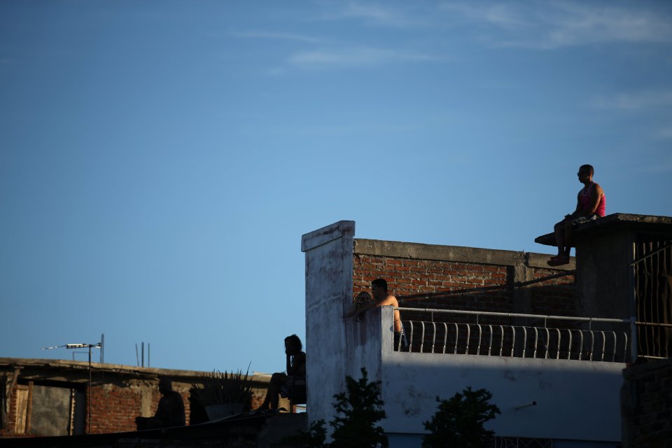  People sit on roof tops while waiting for the funeral procession