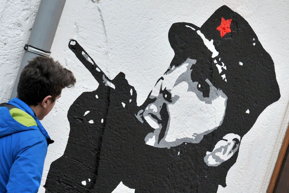  A pedestrian walks past a mural depicting the Cuban revolutionary