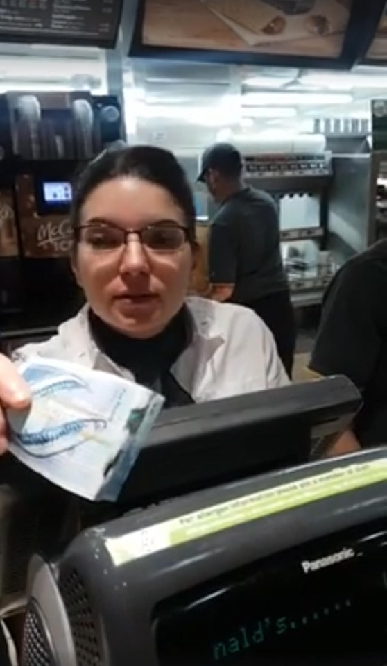  Member of staff behind the tills at McDonald's inspects bill before handing it back to him