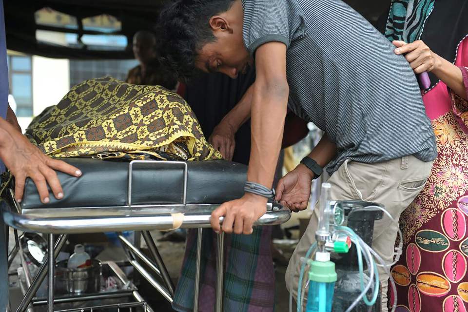  A devastated relative stands over the grave of his dead family member