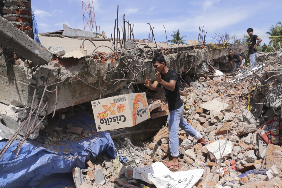  A man removes a box of food from under the rubble of a building that collapsed after the earthquake