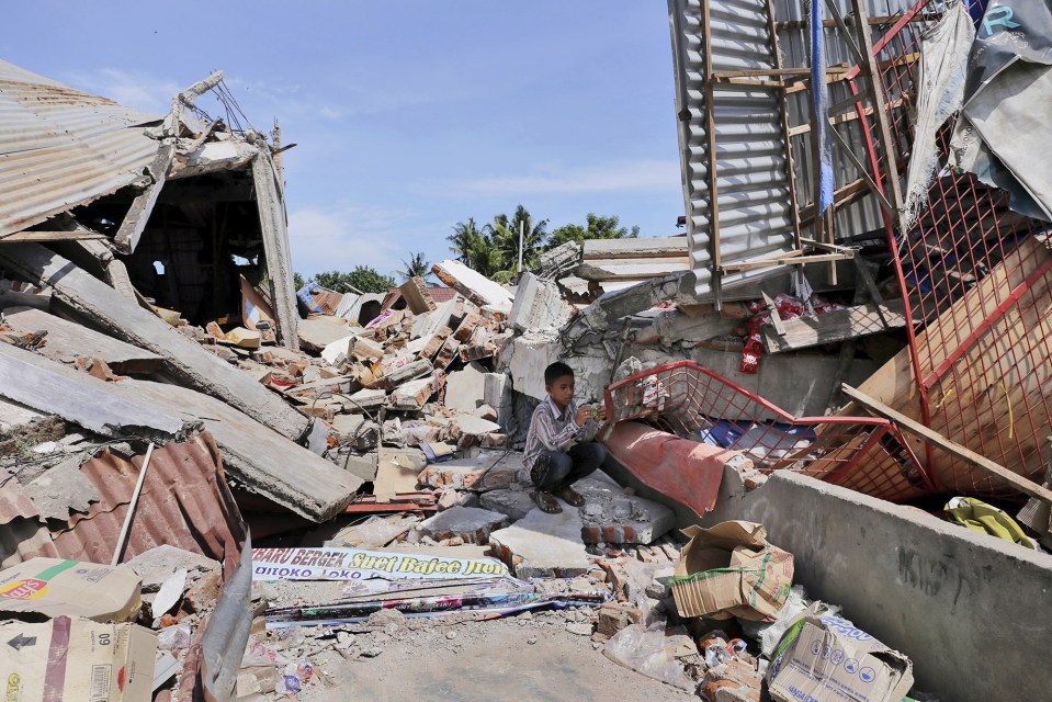  A boy sits on the rubble of a building that collapsed in the horrific natural disaster