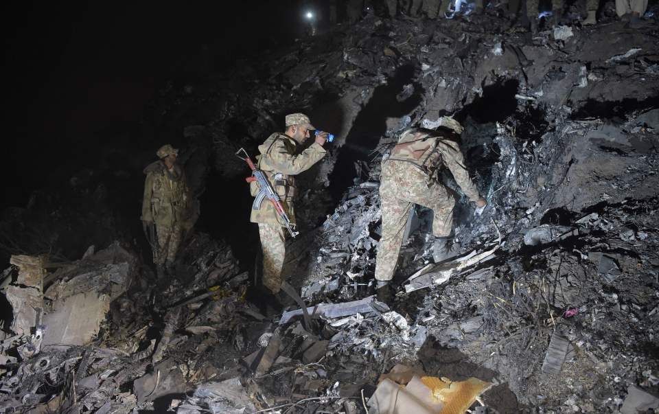  Pakistani soldiers search for victims from the wreckage of the crashed PIA passenger plane