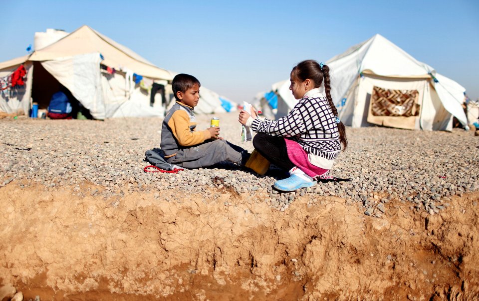  A displaced Iraqi girl who fled the Islamic State stronghold of Mosul teaches her brother out side their tent at Hassan Sham camp, Iraq