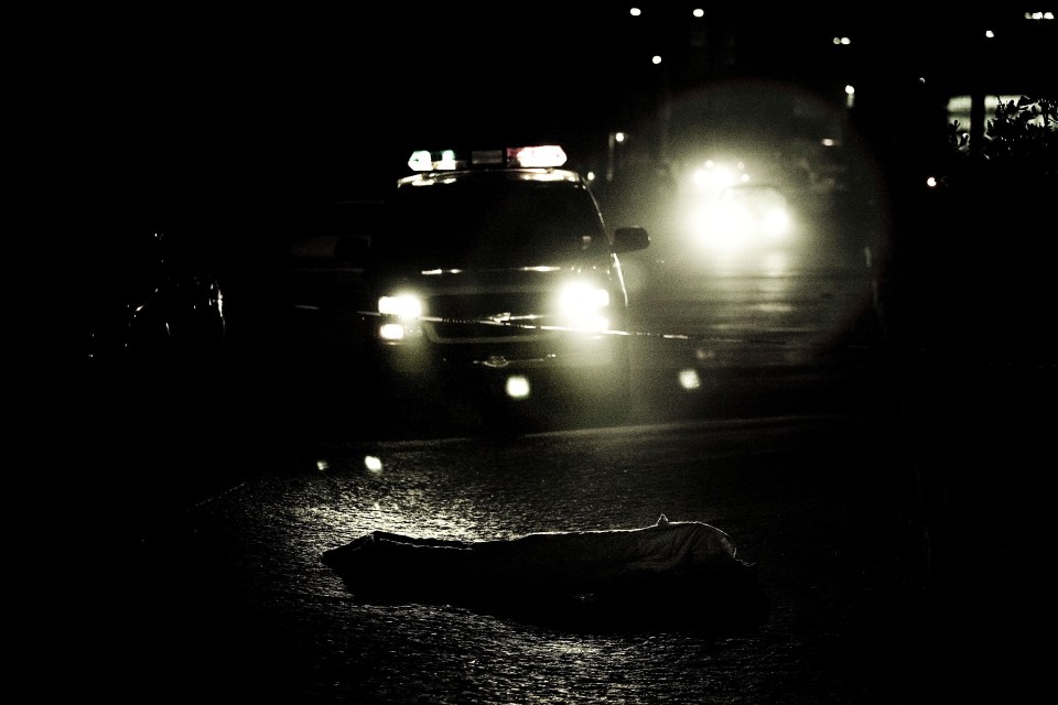  Police headlights illuminate a body in the street during a night operation in the Mexican city of Tijuana