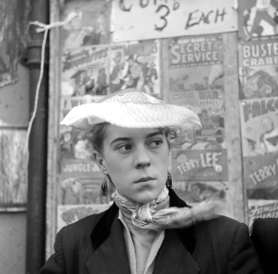  Iris Thornton poses in front of a comic stall in Plaistow while wearing a silk scarf and eye-catching hat