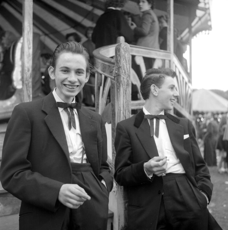  Two teddy boys are photographed smoking and joking around at a funfair in London in 1955