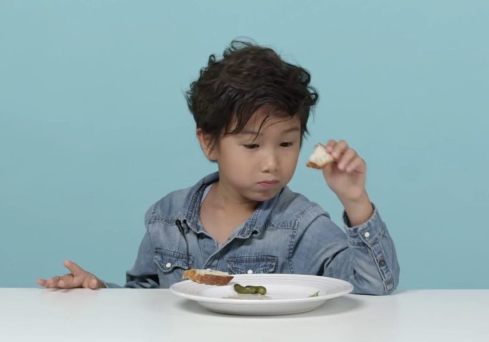 A young boy tucks into his plate of frogs leg and mashed potato 