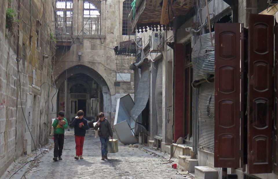  Syrian children walk in the old market in the government-held old city of the northern embattled city