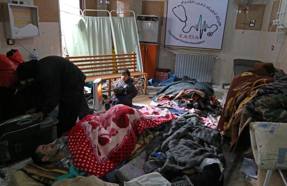  Children warm themselves around a heater as they wait inside a field hospital with injured and sick people to be evacuated