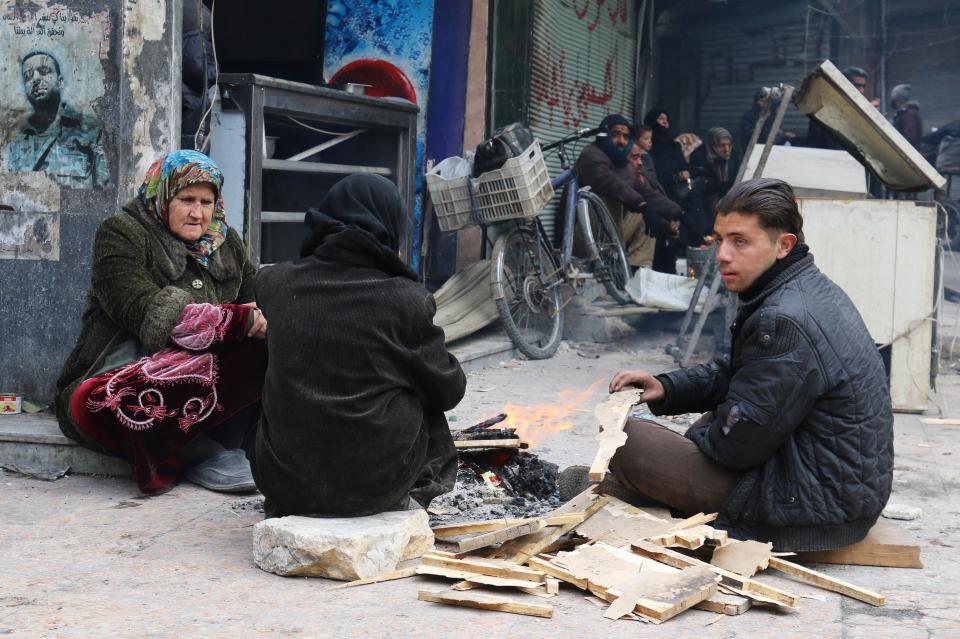  People warm themselves around a fire while waiting to be evacuated from a rebel-held sector of eastern Aleppo