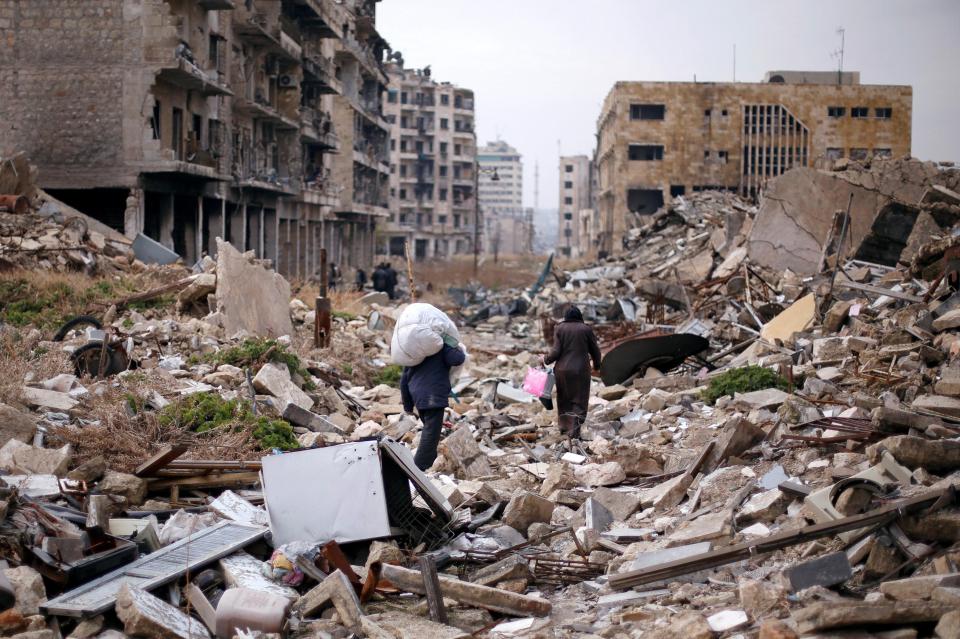  People walk amid the debris as they carry belongings they collected from their houses